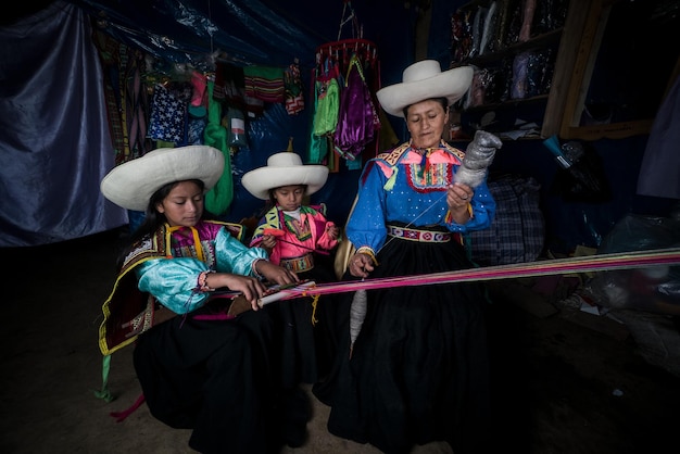 Andyjska matka z Ameryki Łacińskiej, ucząca swoje dziewczynki techniki inkaskiej peruwiańskiego tkania talii