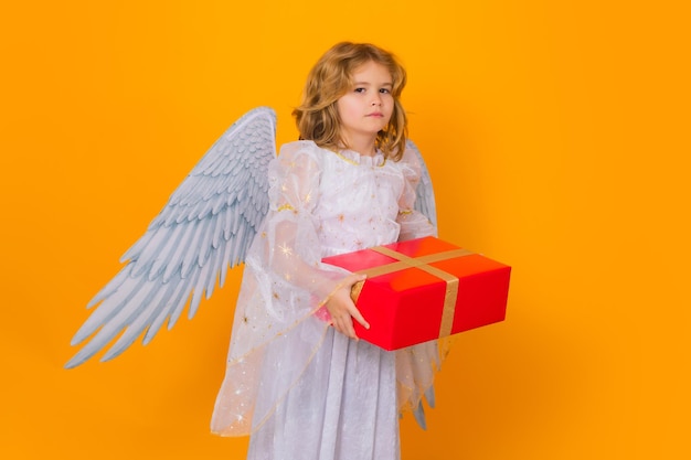 Anioł dziecko trzyma prezent obecny dzieciak ubrany w białą sukienkę anioła i skrzydła z piór niewinne dziecko