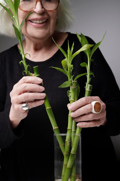 Zdjęcie anonimowa starsza kobieta z rośliną bambusa