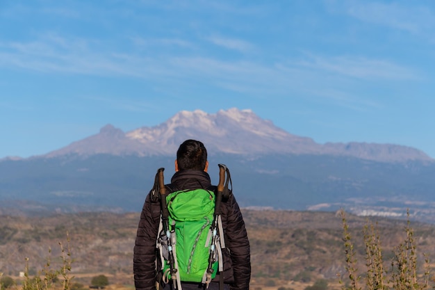 Anonimowy mężczyzna z widocznymi tylko plecami, z widokiem na wulkan iztaccihuatl.