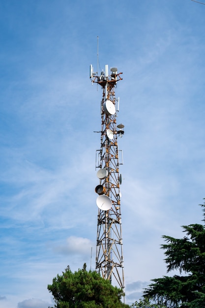 Antena komórkowa na tle błękitnego nieba przy słonecznej pogodzie. Komunikacja.