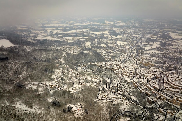 Antenowy zimowy krajobraz gęstego zabytkowego centrum miasta Thiers w departamencie PuydeDome regionu AuvergneRhoneAlpes we Francji Dachy starych budynków i wąskie uliczki przy opadach śniegu