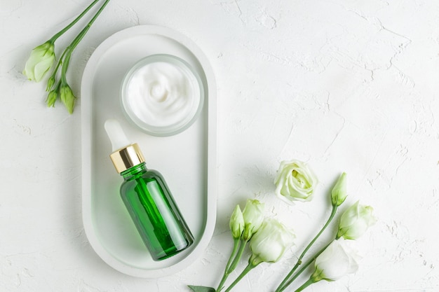 Antiaging kolagenowe serum do twarzy w przezroczystej zielonej szklanej butelce ze złotą pipetą i kremem do twarzy na tacy cwramic na białym tle Natural Organic Cosmetic Beauty Concept