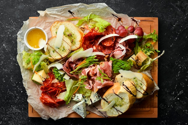Antipasto Włoskie jedzenie Prosciutto kapary salami miód parmezanowy na drewnianej desce Widok z góry Styl rustykalny