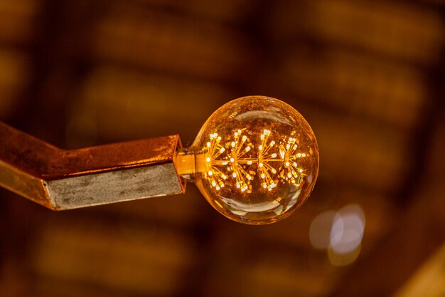Antyczna lampa dekoracyjna z włóknami widocznymi przez szkło, zamazane żółtawe złote tło