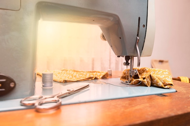 Antyczna maszyna do szycia z nożyczkami skrawkami pomarańczowych tkanin i szpulką nici