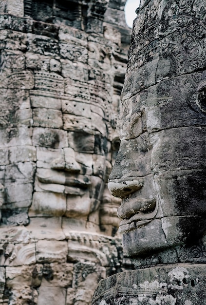 Antyczne kamienne twarze przy niebieskim niebem chmurnym Bayon świątynia, Angkor Wat, Siam Przeprowadzają żniwa, Kambodża.