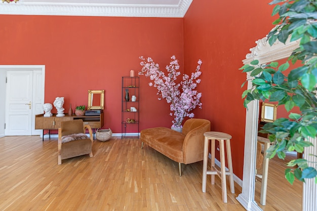 Antyczne zabytkowe wnętrze w XIX-wiecznym salonie w stylu z jasnoczerwonymi ścianami, drewnianą podłogą i bezpośrednim działaniem promieni słonecznych wewnątrz pokoju.