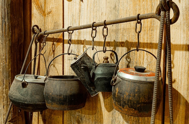 Antyczne żelazne garnki wiszące na żelaznym stojaku w wiejskiej kuchni