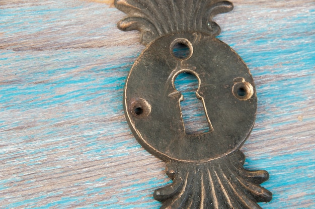 Zdjęcie antyczny mosiądz okładka zamka dziurka od klucza na niebieskim tle drewnianych. skopiuj miejsce na tekst.