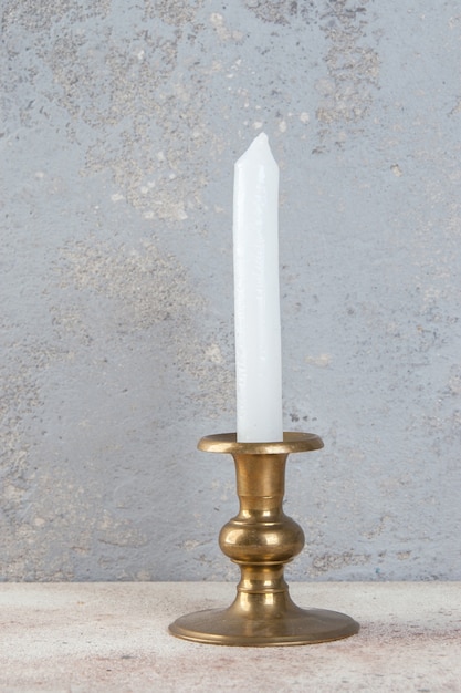 Antyczny mosiężny świecznik na jedną świecę na betonowym tle. Skopiuj miejsce na tekst.