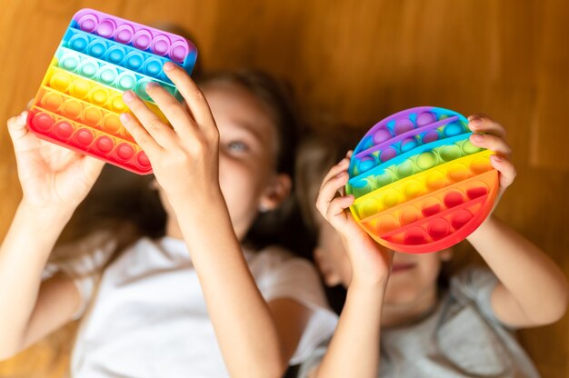 Antystresowe zabawki sensoryczne pop it w dziecięcych rękach. małe szczęśliwe dzieci bawią się w domu prostą zabawką z wgłębieniami.