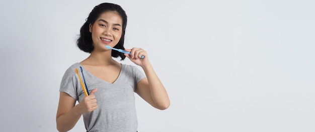 Aparat dentystyczny nastolatka uśmiecha się trzymając szczoteczkę do zębów i patrząc na kamerę