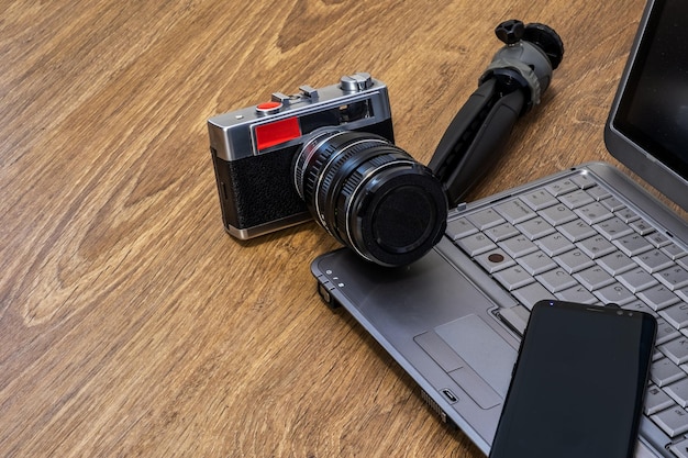 Aparat fotograficzny statyw do laptopa i telefon komórkowy na drewnianym stole
