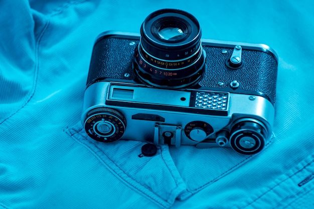 Zdjęcie aparat w stylu retro. zbliżenie retro kamery leżącej na niebieskiej koszuli