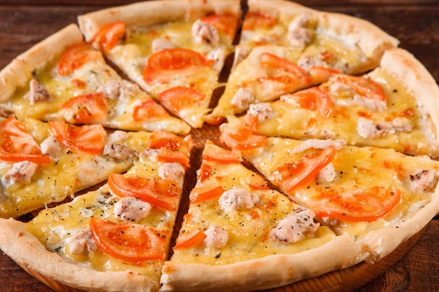 Apetyczna włoska gorąca pizza pokrojona w plastry podana na drewnianym półmisku. Tradycyjna kuchnia, fast food, z bliska.