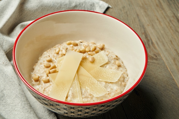 Apetyczne i zdrowe śniadanie - płatki owsiane z parmezanem w misce na drewnianej powierzchni. Ścieśniać. Skopiuj miejsce