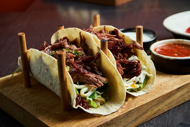 Apetyczne meksykańskie tacos z wołowiną, kapustą, cebulą i natką pietruszki w specjalnych stojakach. Tradycyjna kuchnia meksykańska