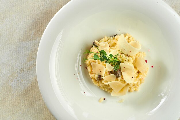 Apetyczne risotto z borowikami i parmezanem w białym talerzu na białym obrusie