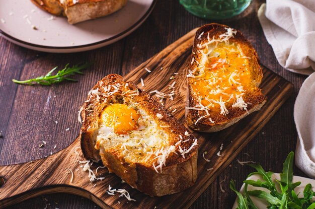 Zdjęcie apetyczny brioche zapiekany z jajkiem i serem na desce