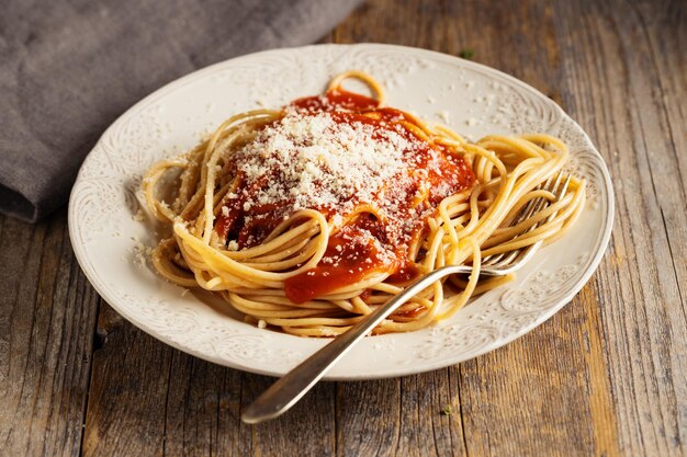 Zdjęcie apetyczny makaron z sosem pomidorowym i parmezanem na talerzu. zbliżenie