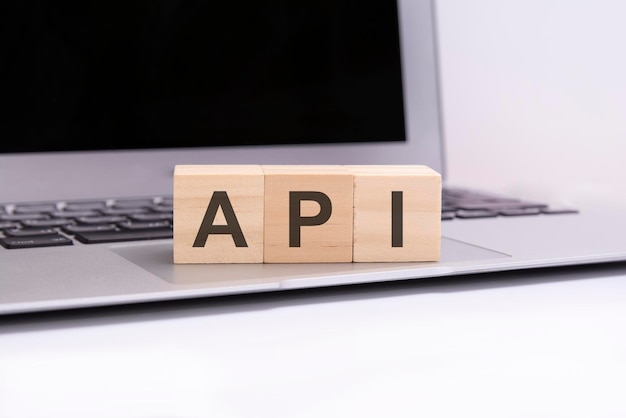 Zdjęcie api - drewniane kostki z literami na srebrnej klawiaturze laptopa. api - skrót od interfejsu programowania aplikacji. biznes koncepcyjne słowo zebrane z drewnianych elementów z literami.