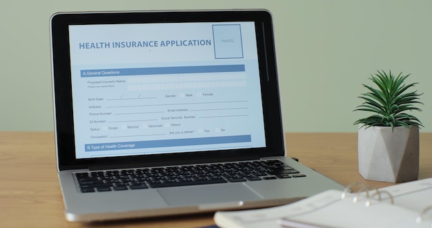Aplikacja ubezpieczenia zdrowotnego online wyświetlana na ekranie komputera przenośnego siedzącego na biurku