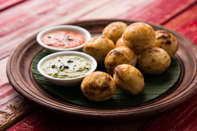 Appam lub Mixed dal lub Rava Appe podawane na nastrojowym tle z zielonym i czerwonym sosem chutney. Kula w kształcie popularnej południowoindyjskiej receptury śniadaniowej. Selektywne skupienie