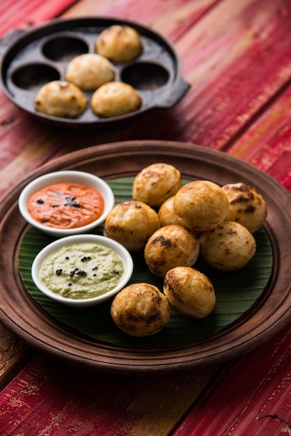 Appam lub Mixed dal lub Rava Appe podawane na nastrojowym tle z zielonym i czerwonym sosem chutney. Kula w kształcie popularnej południowoindyjskiej receptury śniadaniowej. Selektywne skupienie