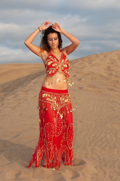 Arabka tańczy taniec brzucha na pustynnych wydmach o zachodzie słońca