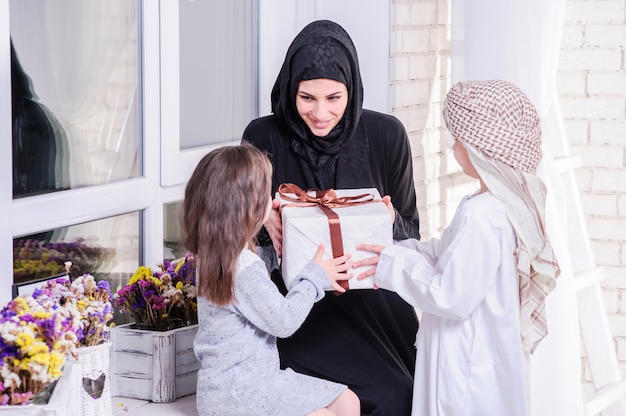 Arabska matka i dzieci pozuje z prezentem.