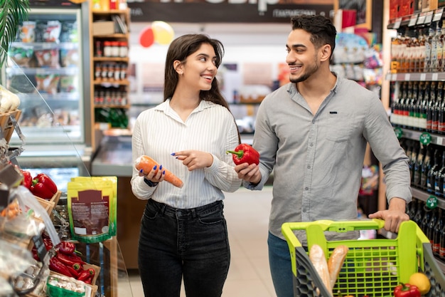 Arabska para kupuje artykuły spożywcze kupując jedzenie wybierając warzywa w supermarkecie