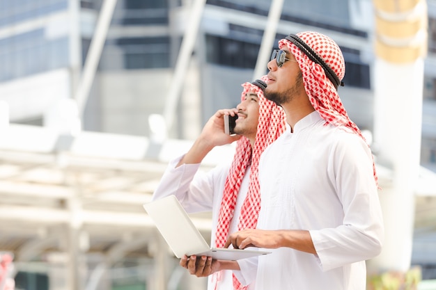 Arabski biznesowy mężczyzna dzwoni telefon pracuje na taplet w mieście