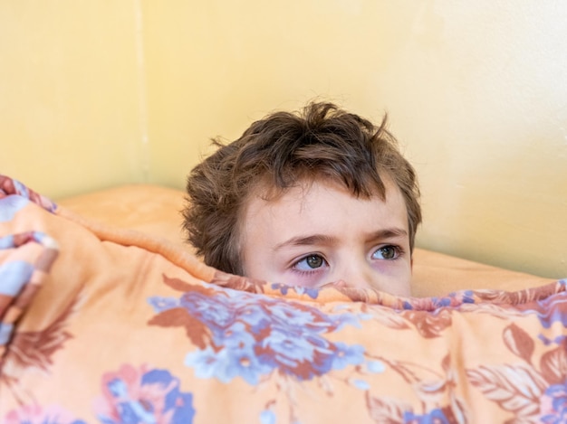 Arabski chłopiec bawiący się w chowanego i chowający się za poduszką