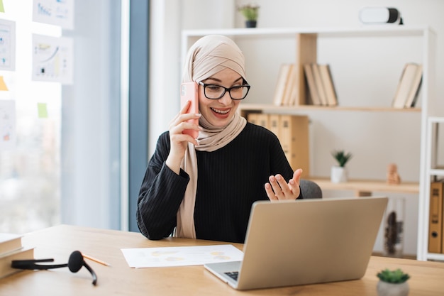 Arabski menedżer rozmawiający przez telefon za laptopem w pracy