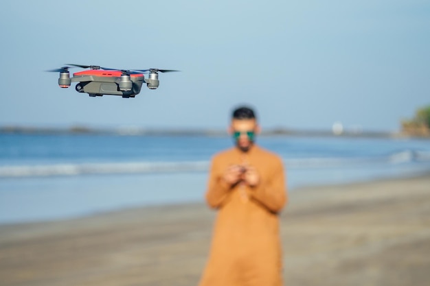 Arabski mężczyzna testujący zdjęcia i wideo z drona na kwadrokopterze nad morzem na plaży Goa