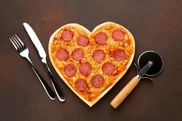 Zdjęcie aranżacja walentynkowa z pizzą w kształcie serca i zastawą stołową