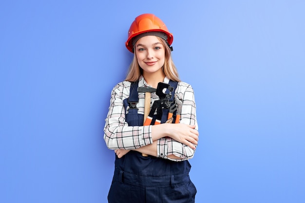 Architekt Biznesu Kobieta W Pomarańczowym Kasku Stojąc Przed Niebieską ścianą, Młoda Kaukaska Kobieta W Mundurze Kombinezonu Pracuje Jako Inżynier Konstruktor