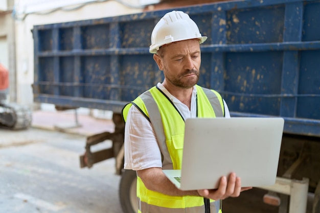 Architekt mężczyzna w średnim wieku za pomocą laptopa na ulicy