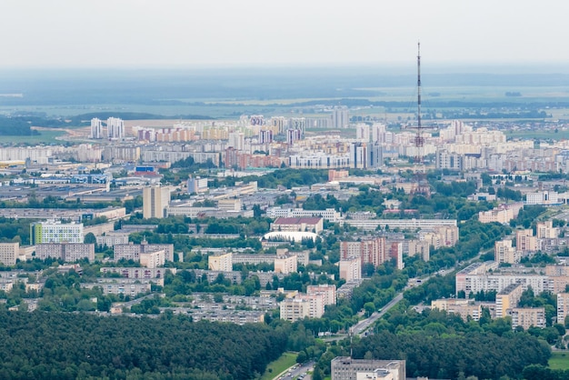 Ariel panoramiczny widok na miasto i drapacze chmur z ogromną fabryką z dymiącymi kominami w tle