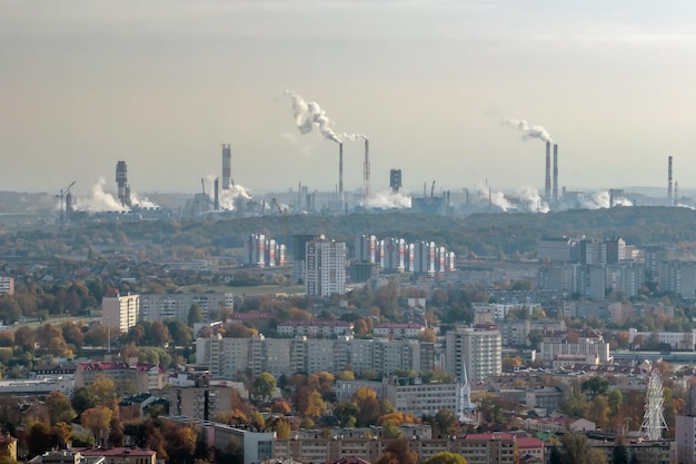 Zdjęcie ariel panoramiczny widok na miasto z ogromną fabryką z dymiącymi kominami w tle