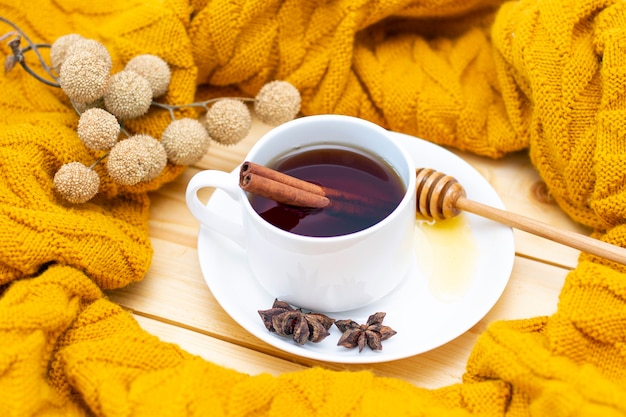 Aromatyczna Gorąca Cynamonowa Herbata Przykryta Ciepłym Szalikiem Na Drewnianym Jesiennym Tle. Miodowa łyżka Z Miodem