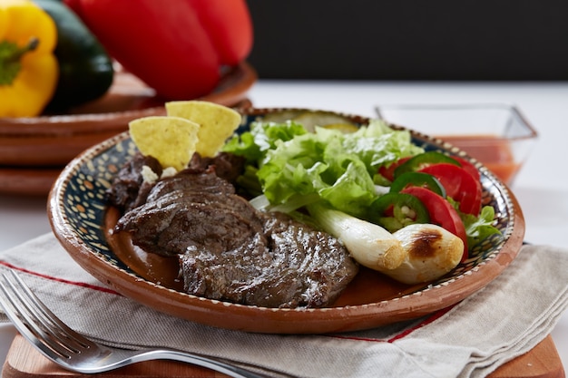 Arrachera Con Frijoles Refritos Cebollinas Y Ensalada Servido En Plato De Barro