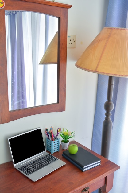 Zdjęcie artykuły biurowe, laptop z notatnikiem i jabłkiem na drewnianym stole