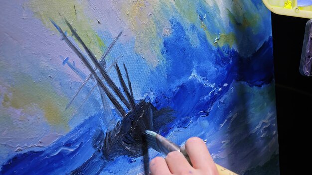 Artysta kopista maluje pejzaż morski ze statkiem na oceanie Rzemieślnik dekorator rysuje jak żagiel łodzi po błękitnym morzu akrylowym kolorem oleju Narysuj palec pędzla paleta