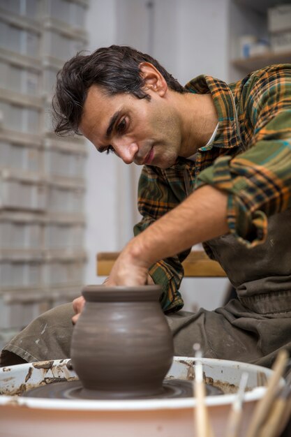 Zdjęcie artysta robi glinianą ceramikę na obrotowym kole w warsztacie