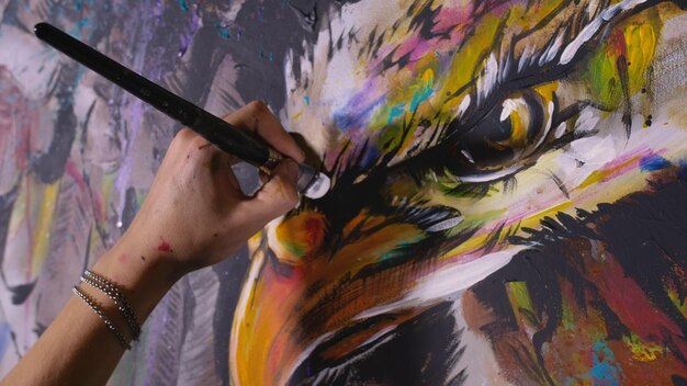 Artysta rysuje orła na ścianie Rzemieślnik dekorator maluje obraz akrylowym pędzlem do farb olejnych Zbliżenie ciemna magia filmowy wygląd