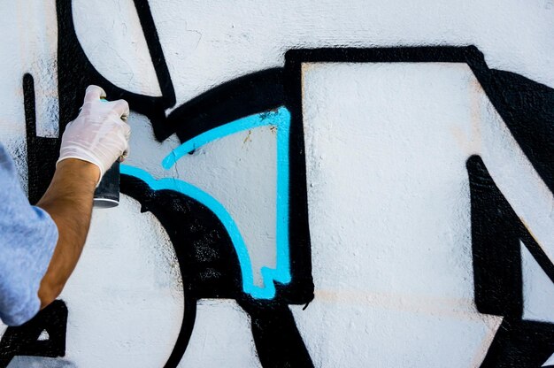 Artysta uliczny rysuje kolorowe i żywe graffiti Nowoczesna koncepcja sztuki z artystą z miasta nakłada jasne graffiti na szarej ścianie