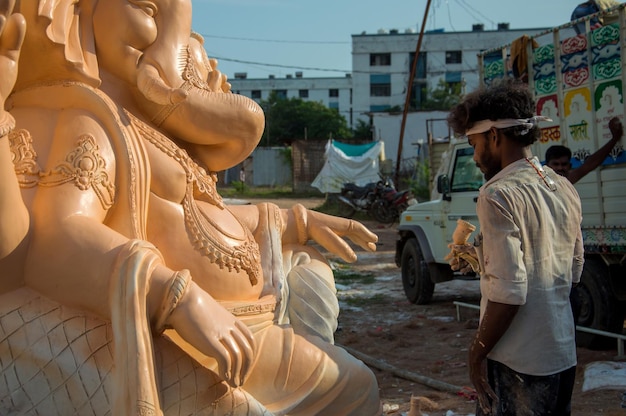 Artysta wykonujący rzeźbę i wykańczający figurkę hinduskiego boga Pana Ganesha w warsztacie artysty na festiwal Ganesha