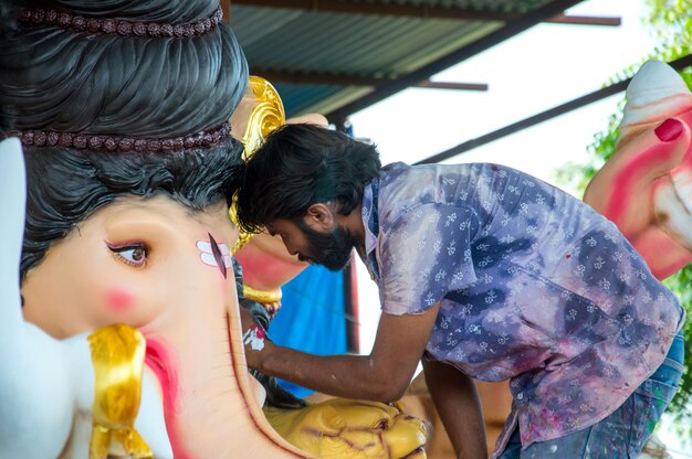 Artysta wykonujący rzeźbę i wykańczający figurkę hinduskiego boga Pana Ganesha w warsztacie artysty na festiwal Ganesha